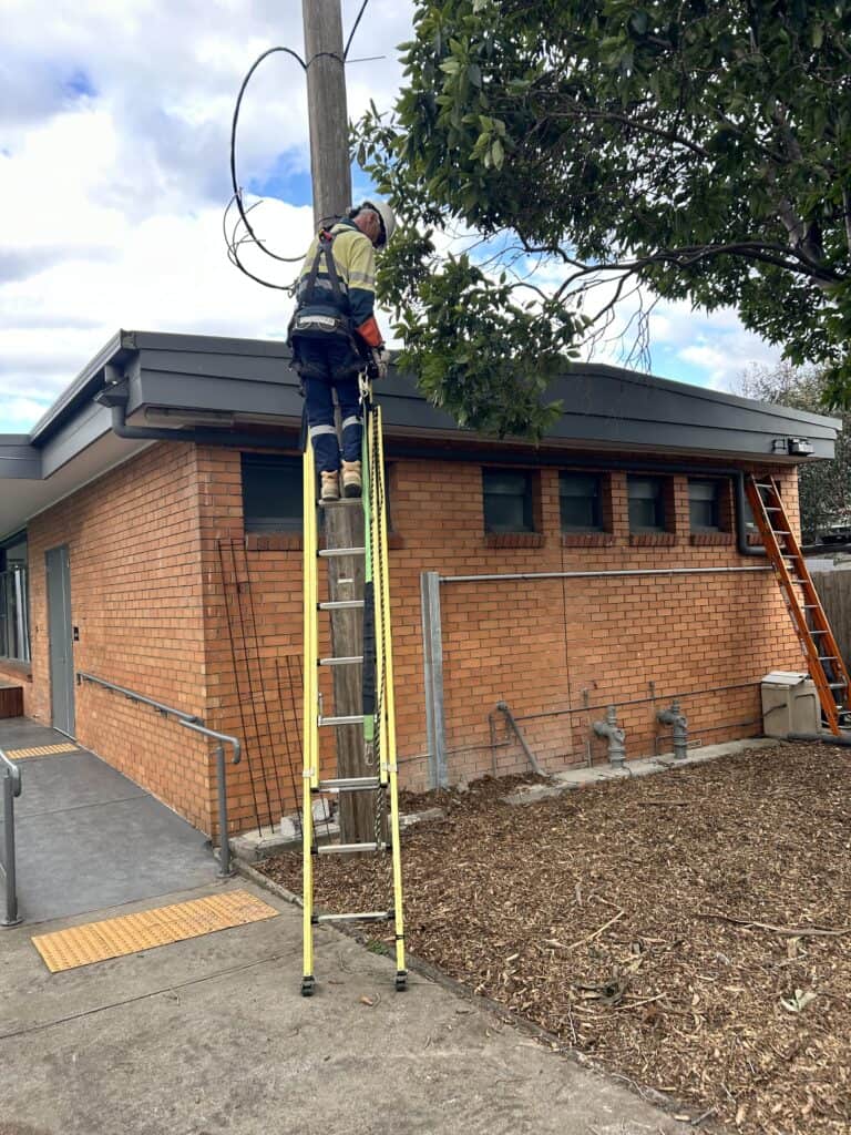 Licensed electrician connecting three phase power cables during professional electrical system upgrade process
